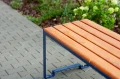 Wooden seat of Frederiksberg 3 Seater Public Backless Bench on a paved path.