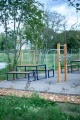 Frederiksberg 3 Seater Public Backless Bench in outdoor park with exercise equipment.