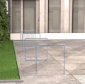 Modern minimalist bike stands Østerbro Bike Stand placed on a concrete pavement next to a green lawn.
