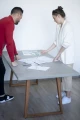 Concrete table in office with two people discussing plans.