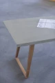 Concrete table with wooden legs in a minimalistic setting.