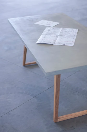 Concrete table with wooden legs and papers on top.
